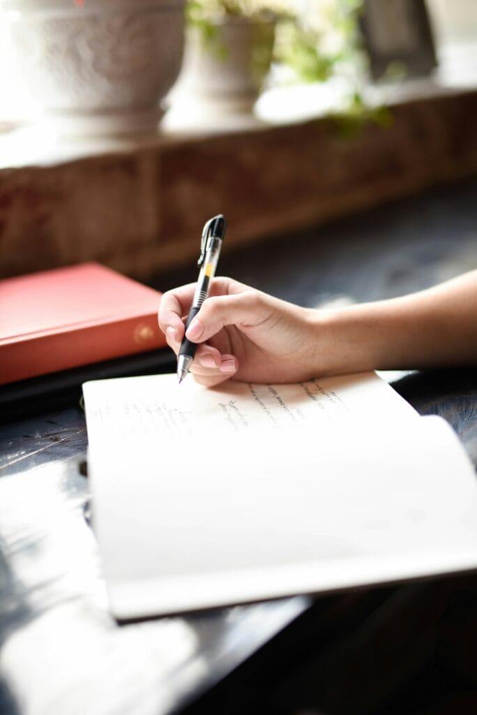 Photo de la main d'une personne tenant un stylo et écrivant dans un cahier